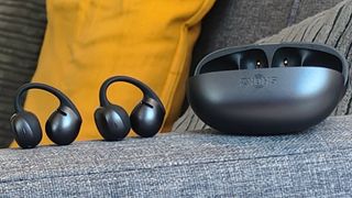 The Shokz OpenDots Air case and earbuds on the arm of a sofa.