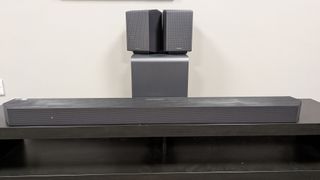 Samsung HW-Q990H soundbar system with the soundbar in front, subwoofer behind and rear speakers stacked on subwoofer