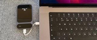 Photograph of the Khadas Tea Pro Headphone Amplifier on a grey fabric surface next to a MacBook Pro